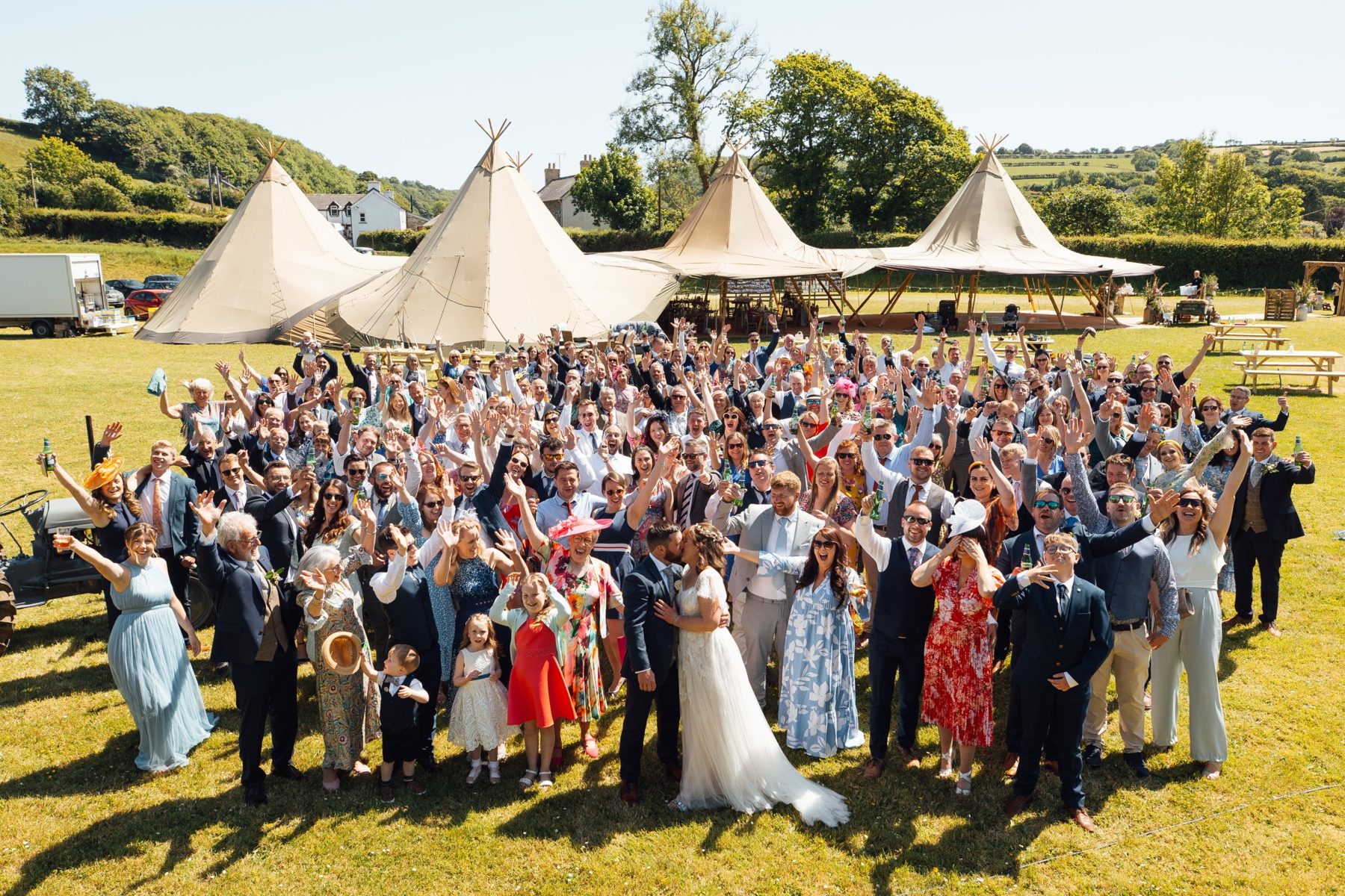 Dafydd and Cadi kissing in front of their cheering guests and four tipis