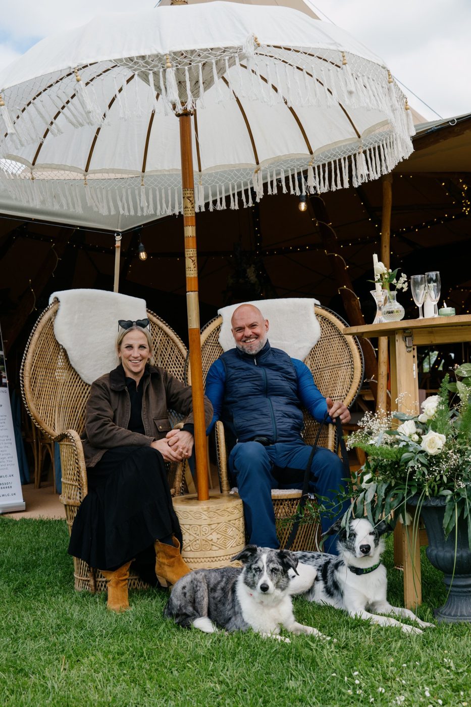 Martha and Nick, owners of Java Tipis, in peacock chairs outside a tipi with their two dogs