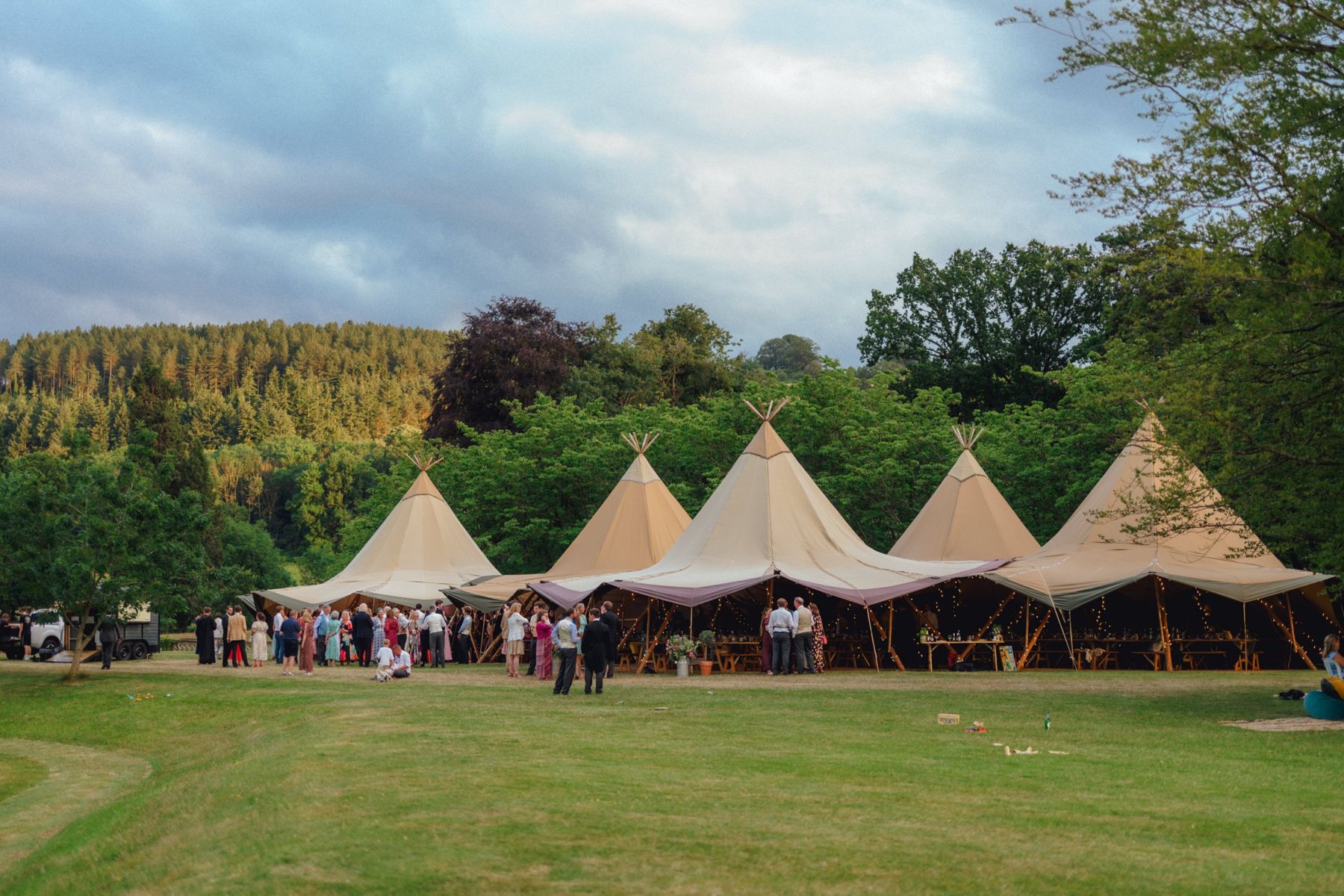 Tatwin and Ellen's guests outside five linked tipis beneath wooded hills